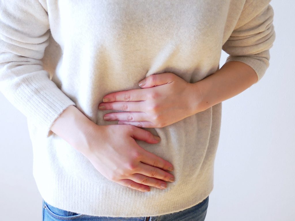 便秘によるお腹の張りを感じ、お腹に手を当てる女性
