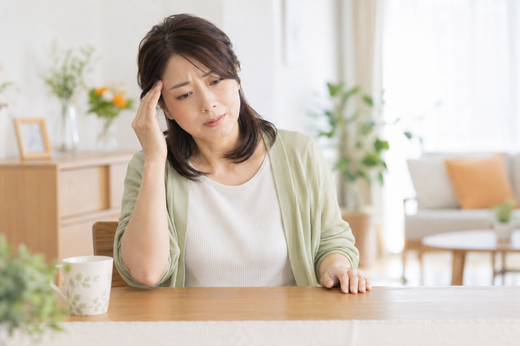頭痛とふらつきを感じ、こめかみに手を当てる女性
